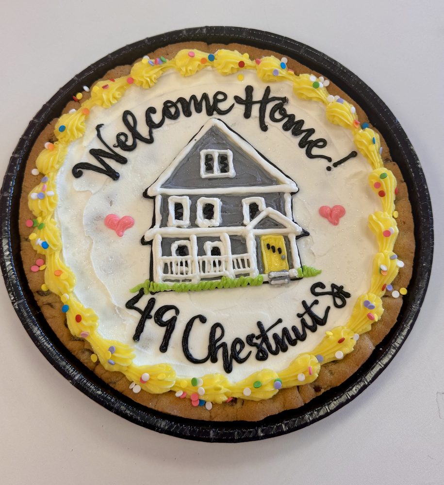 A cookie cake iced with a hand-painted house and the words Welcome Home
