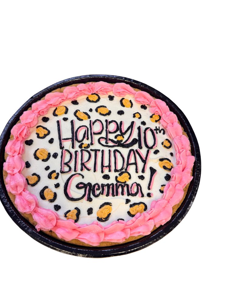 A birthday cookie cake with leopard-print icing and pink piped edging