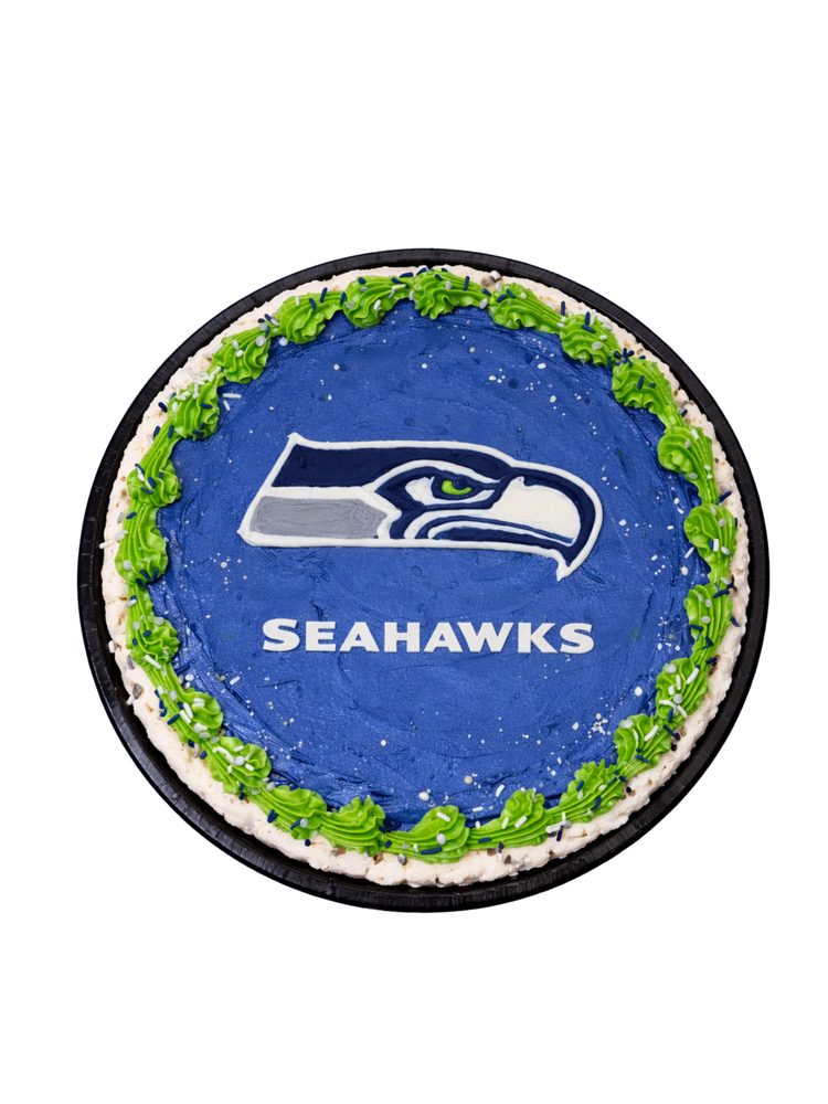 A cookie cake iced with a football team crest on blue, with a green piped border