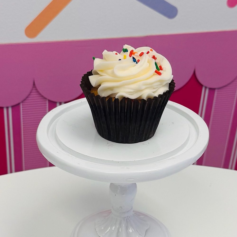 A cupcake with a vanilla buttercream swirl and rainbow sprinkles