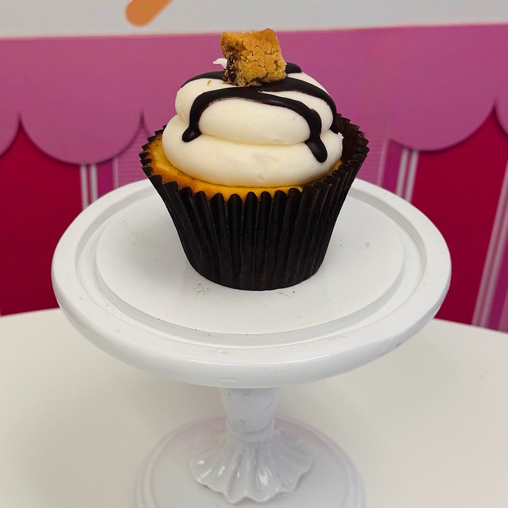 A cupcake with buttercream, a chocolate drizzle and a piece of graham cracker on top