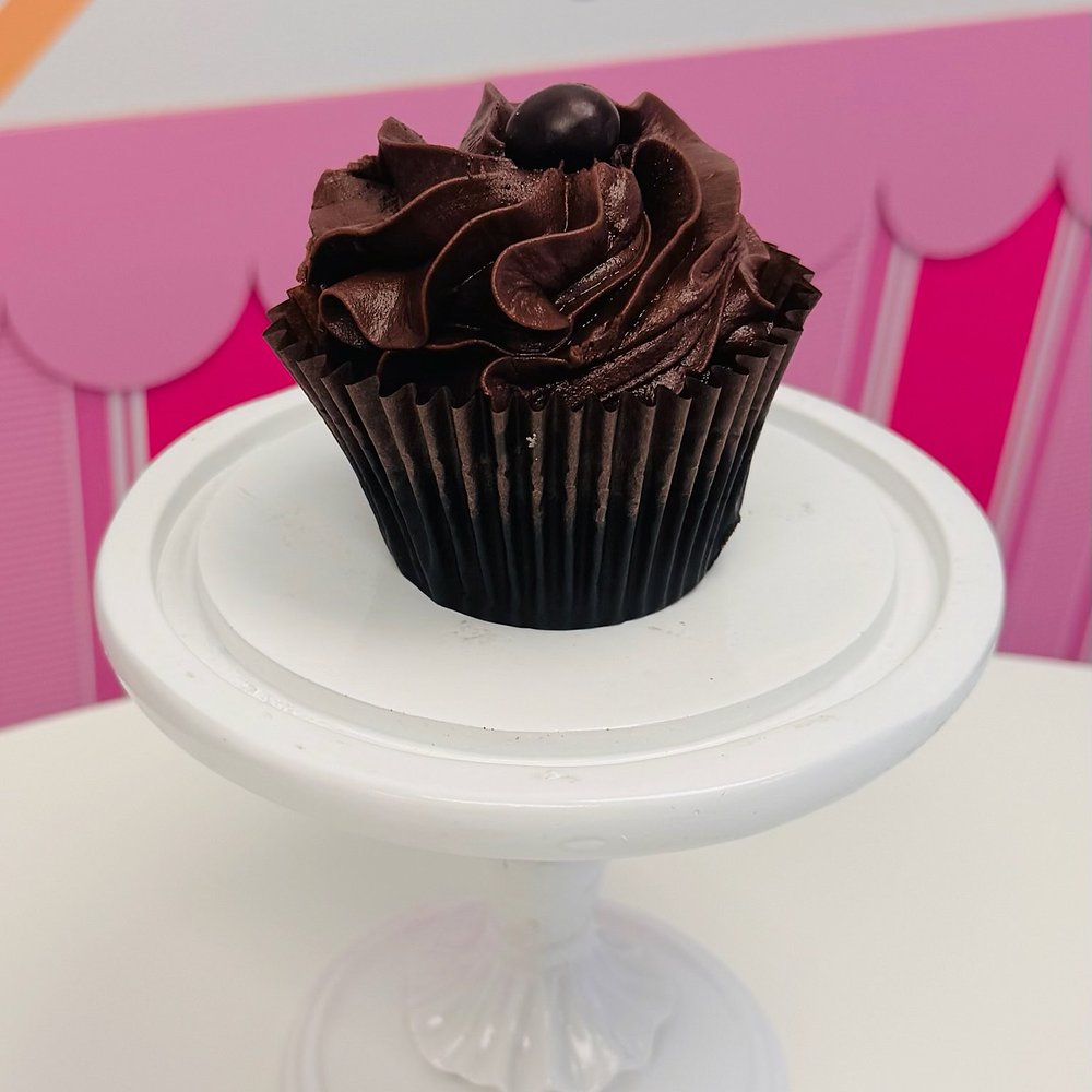 A cupcake with a tall chocolate buttercream swirl topped with a chocolate ball