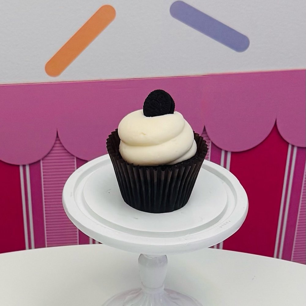 A cupcake with white buttercream and a dark sandwich cookie on top