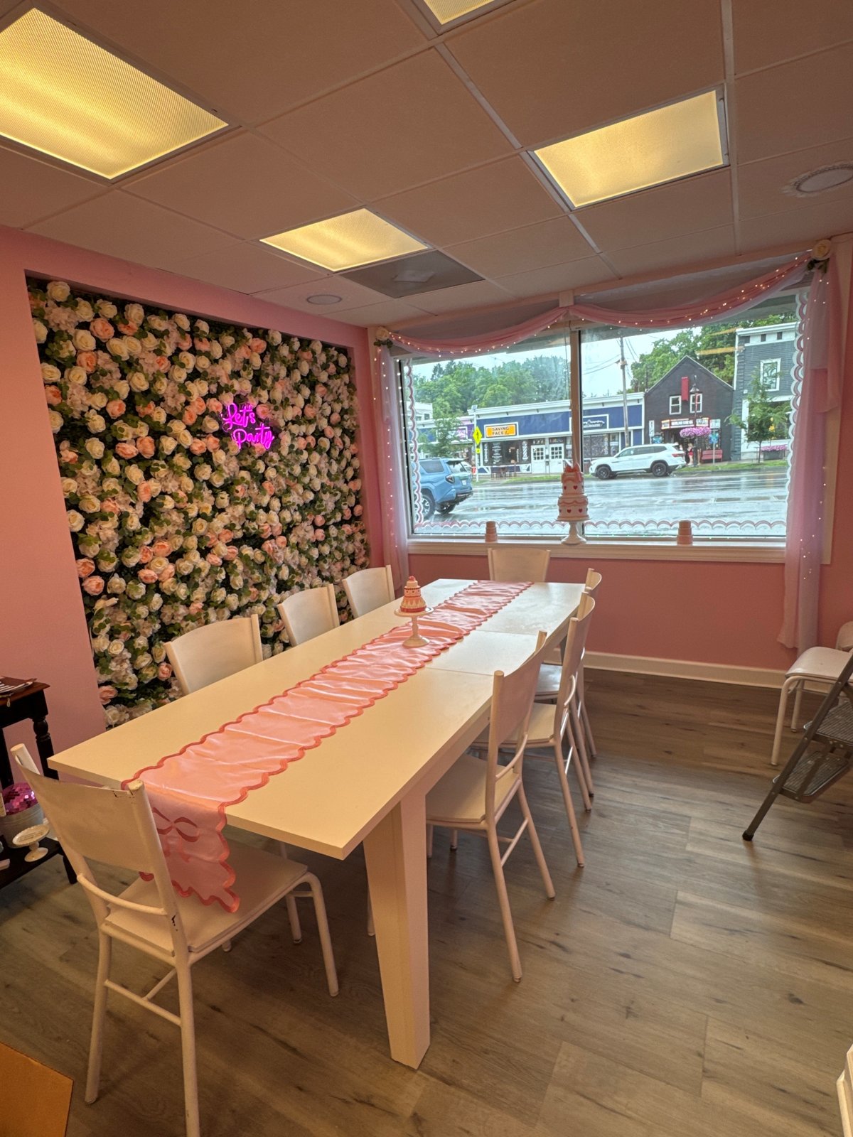 The party room at Mrs. Kelder's Cakes, with a long pink table and floral wall