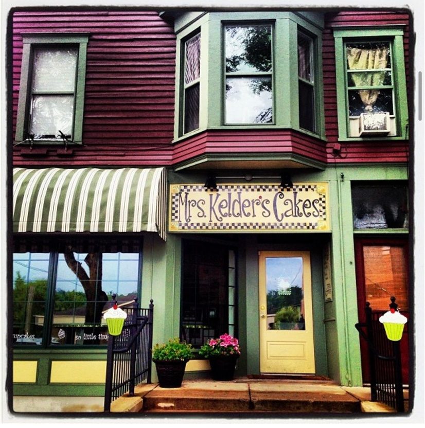 The first Mrs. Kelder's Cakes in 2013, a burgundy and green storefront with a striped awning and yellow door