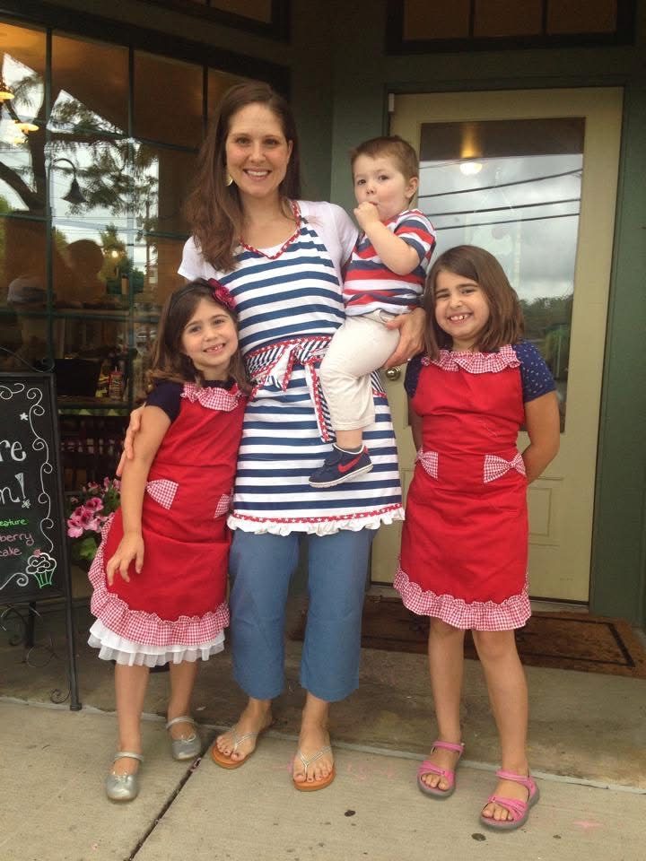 Mrs. Kelder with her three young children in matching red aprons outside the first shop