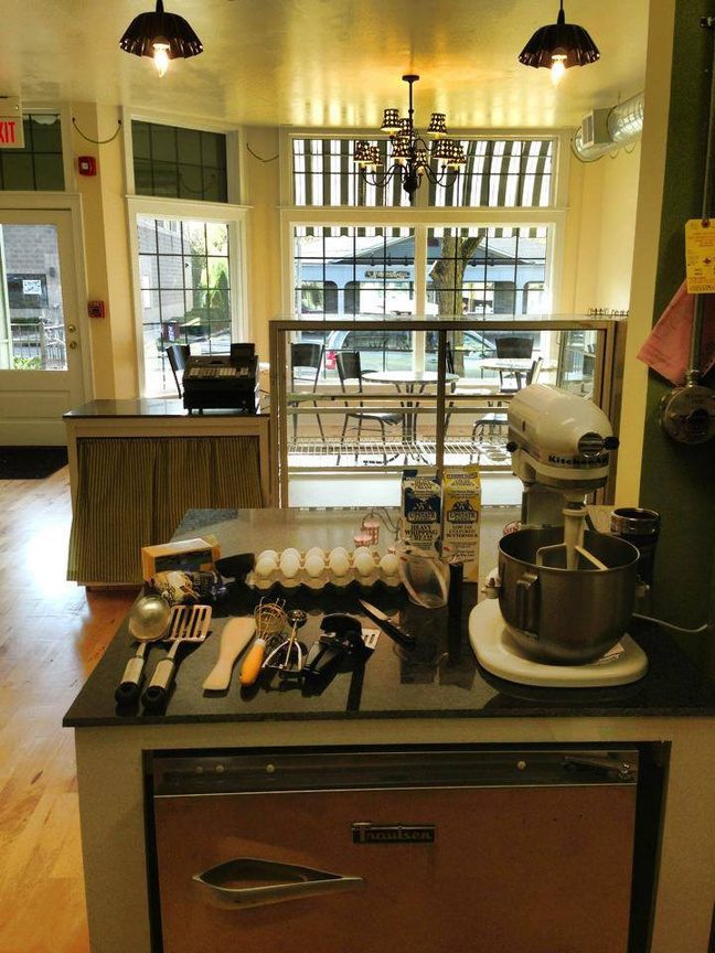 The first shop's kitchen with a stand mixer and cupcakes on the counter
