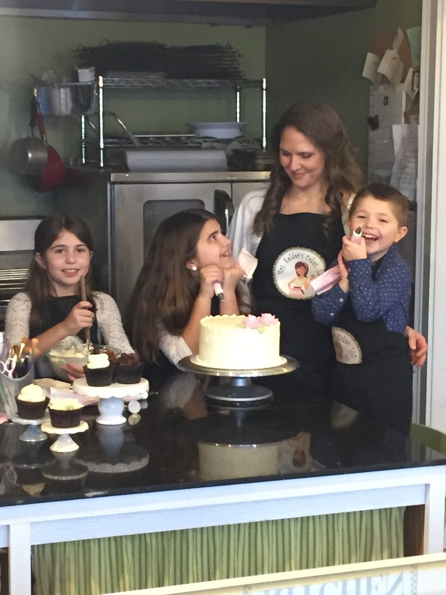 Mrs. Kelder and her kids around a freshly frosted cake in the shop
