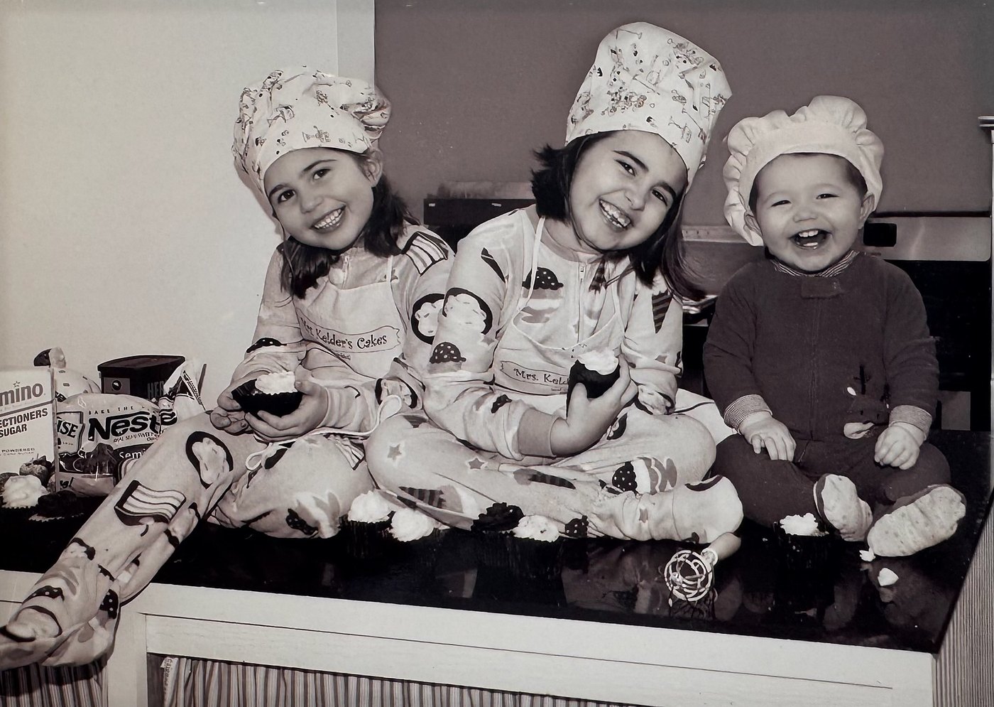 Mrs. Kelder's three children in chef hats and cupcake pajamas on the kitchen counter