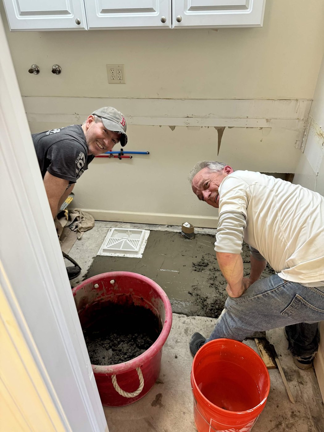 Two helpers on their knees smoothing fresh concrete in the new shop