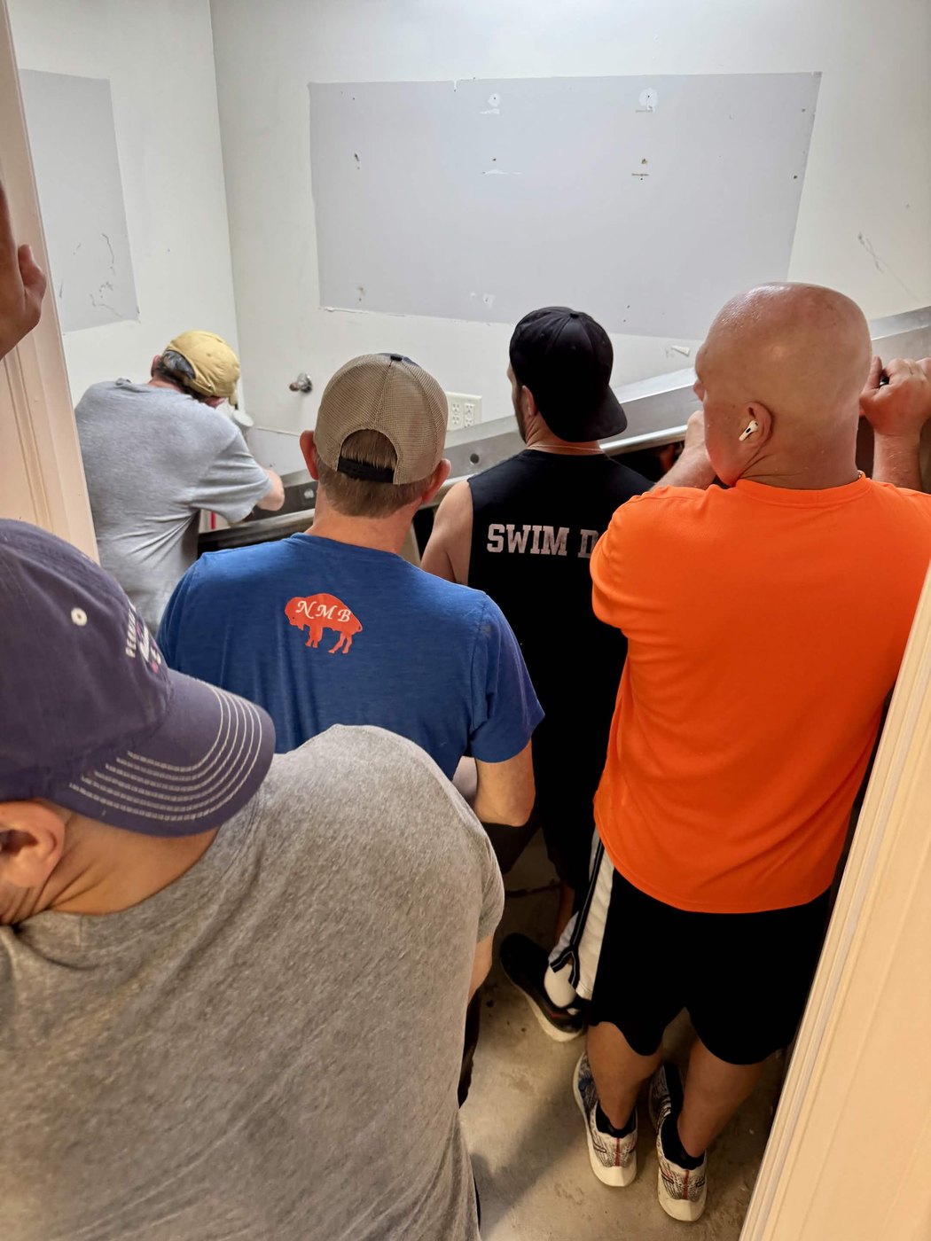 A crowd of friends and family packed into the old kitchen, carrying equipment out