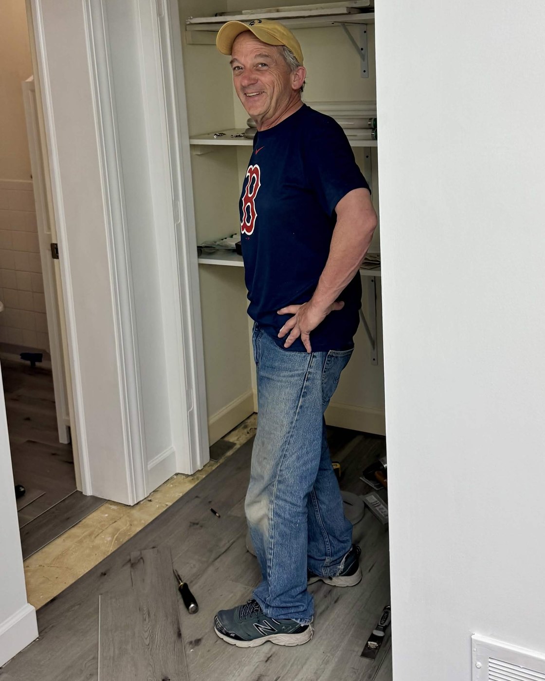 Rich "Papa" Hardy in a yellow cap, standing on the new plank floor he is laying