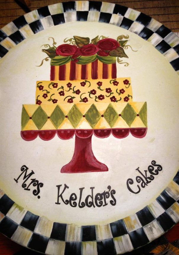A hand-painted plate of a tiered cake reading Mrs. Kelder's Cakes